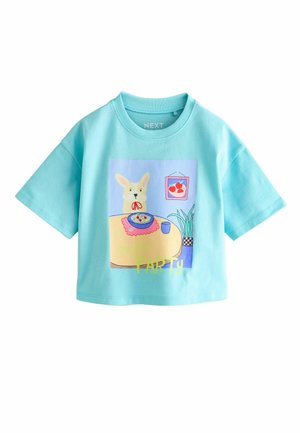 Hellblaues Baumwoll-T-Shirt mit kurzen Ärmeln, das einen Cartoon-Hasen mit einem Teller Pasta, einer Pflanze und dem Text "PASTA PARTY" in leuchtenden Farben zeigt.