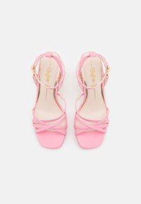 Rosa sandaletter med høye hæler og firkantet tådesign, med kryssede stropper og gullspenne på ankelstroppen. Glatt tekstur.