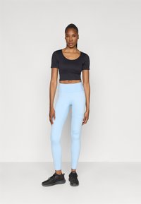 Black cropped t-shirt, light blue leggings, and black athletic shoes. Leggings have a smooth texture and a high waist design.