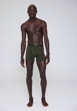Mørke olivengrønne boxer shorts med en sort talje, lavet af blødt stof, med et tætsiddende design og længde til midt på låret.