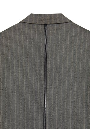 Tissu gris à motif en chevrons avec un col montant et une fermeture éclair noire centrale à l'arrière. La texture est tissée et structurée.