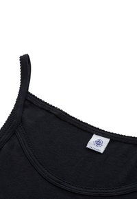 Top nero senza maniche con spalline sottili, scollatura rotonda e bordo a scallop. Realizzato in tessuto morbido, l'etichetta mostra la taglia XS e le informazioni sul marchio.