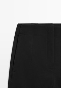 Czarne, dopasowane spodnie garniturowe wykonane z gładkiej tkaniny, z usztywnionym pasem i minimalistycznym designem z ukrytymi bocznymi kieszeniami.