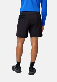 Pantalones cortos deportivos negros con una cinturilla texturizada, combinados con una camiseta de manga larga azul y zapatillas de correr negras con detalles en blanco.