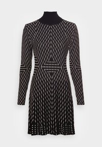 Schwarzes Strickkleid mit hohem Kragen, das ein geometrisches Muster aus weißen und cremefarbenen Zickzacklinien sowie langen Ärmeln aufweist. Strukturierter Stoff.