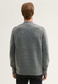 Grauer Strickpullover mit Rundhalsausschnitt, gerippten Bündchen und Saum, der eine strukturierte Oberfläche aufweist. Sichtbare Nähte am Hals.