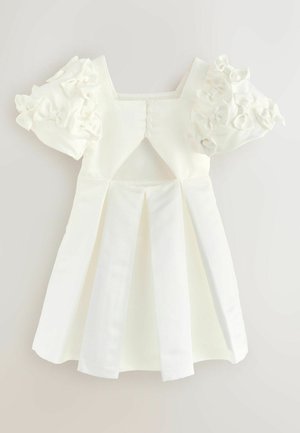 Balta kleita ar īsām, viļņotām piedurknēm un kvadrātveida dekoltē. Iekļauj izgriezumu mugurpusē un pleitu svārkus tekstūras un detaļu pievienošanai.