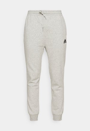 Pantaloni della tuta grigi in morbido tessuto, con vita elastica e cordino regolabile, e logo Adidas nero sulla gamba sinistra.