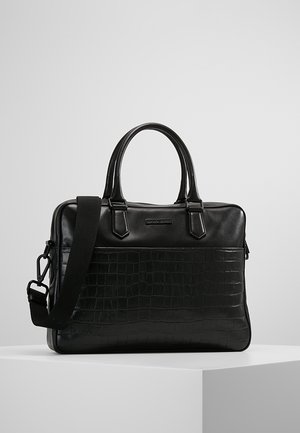 Zwarte leren aktetas met krokodillenprint aan de voorzijde, dubbele handvatten en verstelbare schouderriem, geplaatst op een wit voetstuk tegen een grijze achtergrond.