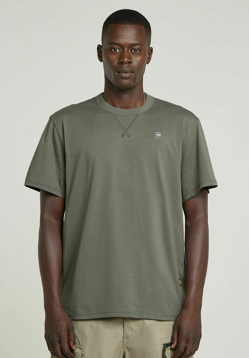 T-shirt à manches courtes vert olive, en coton, avec un col rond à bords côtelés et un petit logo sur la poitrine. Conception à ourlet plat.