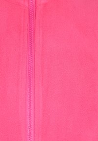 Fényes rózsaszín bolyhos dzseki sima textúrával, középső cipzárral, azonos színben, és magas galléros dizájnnal.