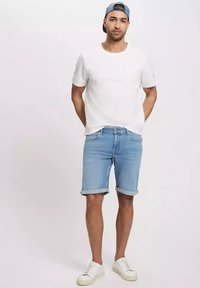 Męski strój składający się z białej bawełnianej koszulki, jasnoniebieskich szortów denimowych i białych trampek. Szorty mają podwinięte nogawki.