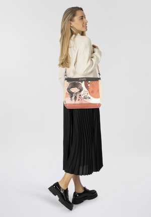 Mehrfarbige Handtasche mit einer fantasievollen Illustration, die ein markantes Charakterdesign und weiche Materialien zeigt. Der Tragegurt ist verstellbar.