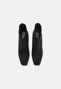 Stivaletti ankle in suede nero con design a punta, caratterizzati da una texture liscia e un logo sulle sole interne.