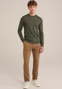 Green knit sweater with a round neckline, slim fit, paired with light brown chinos and white sneakers. Smooth texture, casual design.