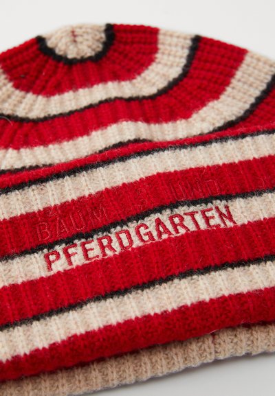 Punane, beež ja must triibuline kudumismüts, millel on tikitud tekst "PFERDGARTEN" ja hägune "BAUM UND PFERDGARTEN" villa kangal.