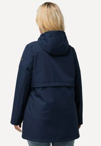 Marinblå vattentät jacka med huva, med en slät yta och en horisontell söm över ryggen. Enkelt design, långa ärmar och ingen synlig hårdvara.