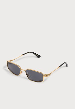 Lunettes de soleil rectangulaires avec monture en métal doré, verres gris foncé et branches noires reposant sur un fond clair.