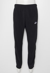 Svarta fleece-joggingbyxor med elastisk midja, avslutade ben och en vit Nike-logotyp på den övre vänstra sidan. Mjuk textur och enkel design.