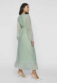 Mintgrønn, langermet kjole med prikkemønster, gjennomsiktige ermer og volangkjole. Brukt med off-white spisse hæler.