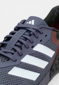 Navy blue athletic shoe with mesh fabric, white stripes, and rubber accents. Features include adjustable lacing and textured outsole.