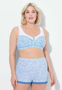 Blå blommönstrad bralette med vita band och spetsdetaljer. Matchande högmidjade shorts med en liknande blommönster och blå spetsdetalj.
