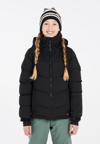 Doudoune noire avec fermeture éclair à l'avant, capuche et poignets élastiques, associée à un pantalon vert et un bonnet rayé noir et blanc.