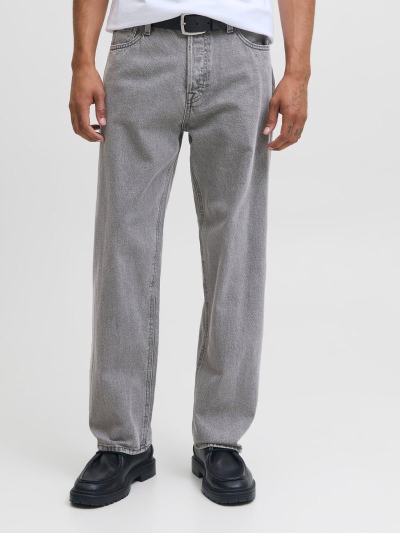 Jeans de denim gris con un corte relajado, que presentan una textura sutil. Combinados con zapatos de cuero negros y un cinturón negro. Diseño minimalista.