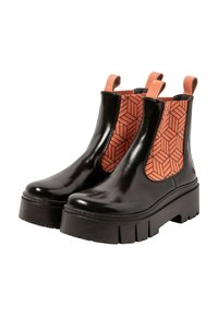 Botas de tobillo de charol negro con un panel lateral elástico naranja de patrón geométrico, tiradores y una suela gruesa negra.