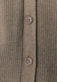 Bruine ribgebreide cardigan met twee ronde bruine knopen aan de voorkant, die de gestructureerde stof en knoopdetails benadrukken.
