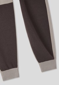 Ciemnobrązowe i jasnoszare spodnie dresowe z ściągaczami, charakteryzujące się kolorowym wzorem oraz miękkim, teksturowanym materiałem.