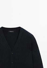 Svart ribbad stickad kofta med V-ringning och två knappar, med en etikett som läser "Massimo Dutti" vid kragen.