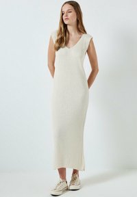 Ribadest kreemivärvi midi kleit V-kaelusega ja lühikeste varrukatega, valmistatud pehmest kangast, koos mugavate kreemivärvi tossudega.