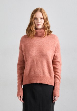 Lys rosa, løs passende genser med ribbestrikket høyhalset krage, lange ermer og avslappet kant. Myk tekstur med en litt loete utseende.