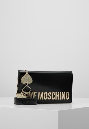 Pochette Love Moschino en cuir noir avec lettrage logo doré, bandoulière chaîne dorée, et pendentifs dorés en forme de cœur, étoile et carré attachés.