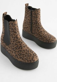 Botki za kostkę w print leopardzi, wykonane z miękkiego materiału, z czarnym elastycznym bokiem i grubą platformą. Zamek błyskawiczny i okrągły czubek.
