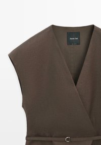 Tmavě hnědé šaty bez rukávů se zavinovacím stylem, výstřihem do V a tenkým páskem s kovovou přezkou v pase, značka Massimo Dutti, vyrobené v Maroku.