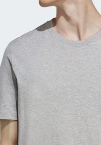 Camiseta gris de manga corta hecha de tejido suave, con cuello redondo y una textura lisa, adecuada para el uso cotidiano.