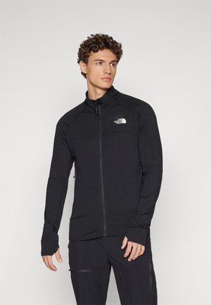 Crna zip-up jakna s teksturiranim materijalom, prilagođenim dizajnom, visokim ovratnikom i logotipom na prsima. Ima uske manžete i bočne džepove.