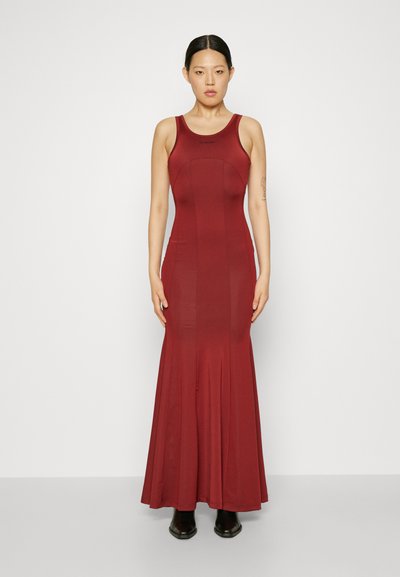 Tvarovo priliehavé, bezrukávové červené šaty s dlhou rozšírenou sukňou. Vyrobené z hladkého materiálu, majú okrúhly výstrih a minimálne švy.
