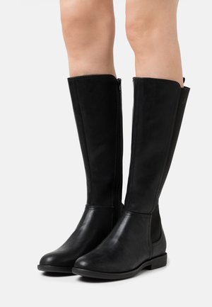 Botas de cuero negro hasta la rodilla con cremallera lateral, punta redondeada y tacón bajo. Textura suave con inserciones elásticas para mayor comodidad.