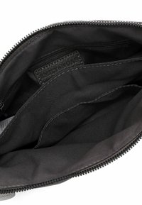 Black fabric interior of a bag, featuring a zip closure and a small label sewn into the lining with the name "EMILY & NOAH."
