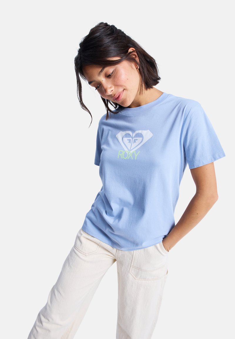 Světle modré bavlněné tričko s kulatým výstřihem a krátkými rukávy, s bílým a neonově zeleným srdcovým logem s textem "ROXY" uprostřed.