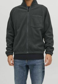 Tmavě šedá fleecová bunda s předním zipem, vysokým límcem a kapsou na hrudi. Žebrovaný lem a manžety, s hladkou texturou.
