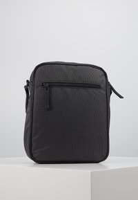 Schwarze Nylon-Crossbody-Tasche mit glatter Oberfläche, quadratischer Form, vorderer Reißverschlusstasche und dezentem Punktmuster. Verstellbarer Tragegurt angebracht.