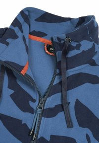 Sininen fleece-takki tummansinisellä kamouflagekuviolla, vetoketjukiinnitys edessä ja oranssit accenttisaumat. Varustettu säädettävällä narulla kauluksessa.
