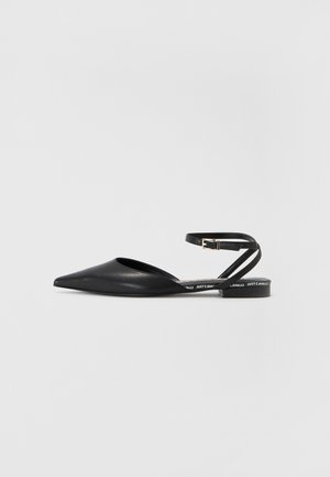 Zapatos de tacón bajo de cuero negro con punta afilada, tacón plano y una correa minimalista en el tobillo con cierre de hebilla. Logo de la marca en la suela.
