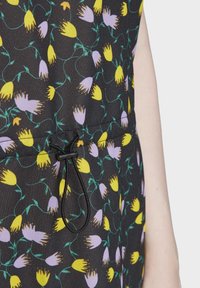Černá látka se květinovým vzorem v žlutých a levandulových květech, doplněná o šňůrkový detail v pase.