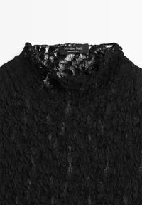 Vêtement à col haut en dentelle noire avec motif floral texturé et étiquette Massimo Dutti cousue à l'intérieur du col.