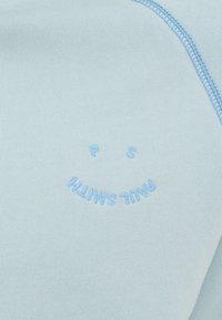 Hele taevasinine spordijakk pehme tekstuuriga, millel on sinine broderiseeritud kiri "PAUL SMITH" ja naeratava näo kujundus. Minimalistlik disain, igapäevane stiil.